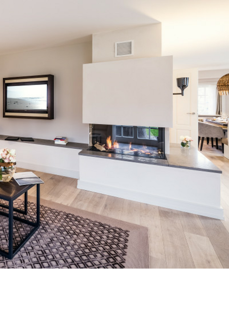 Zimmer & Suiten Wohnbereich mit Kamin Helles Wohnzimmer im Severin*s Resort mit modernem Kamin, gemütlicher Sitzecke und stilvollem Essbereich im Hintergrund.