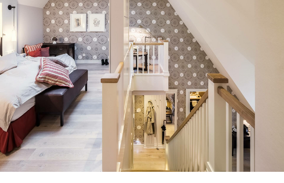 Cozy hotel room with double bed, staircase and stylish wallpaper at Severin*s Resort & Spa on Sylt.