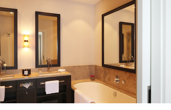Luxuriöses Badezimmer im Hotel Severin*s, mit Doppelwaschbecken, großer Badewanne und eleganter Beleuchtung.