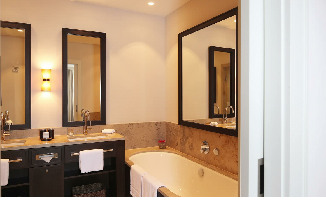 Elegantes Badezimmer mit Doppelwaschbecken, großer Spiegel, Badewanne und sanfter Beleuchtung im Severin*s Resort & Spa.