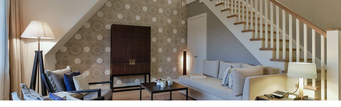 Elegant living room at Severin*s Resort with sofa, armchairs, staircase and stylish lighting.
