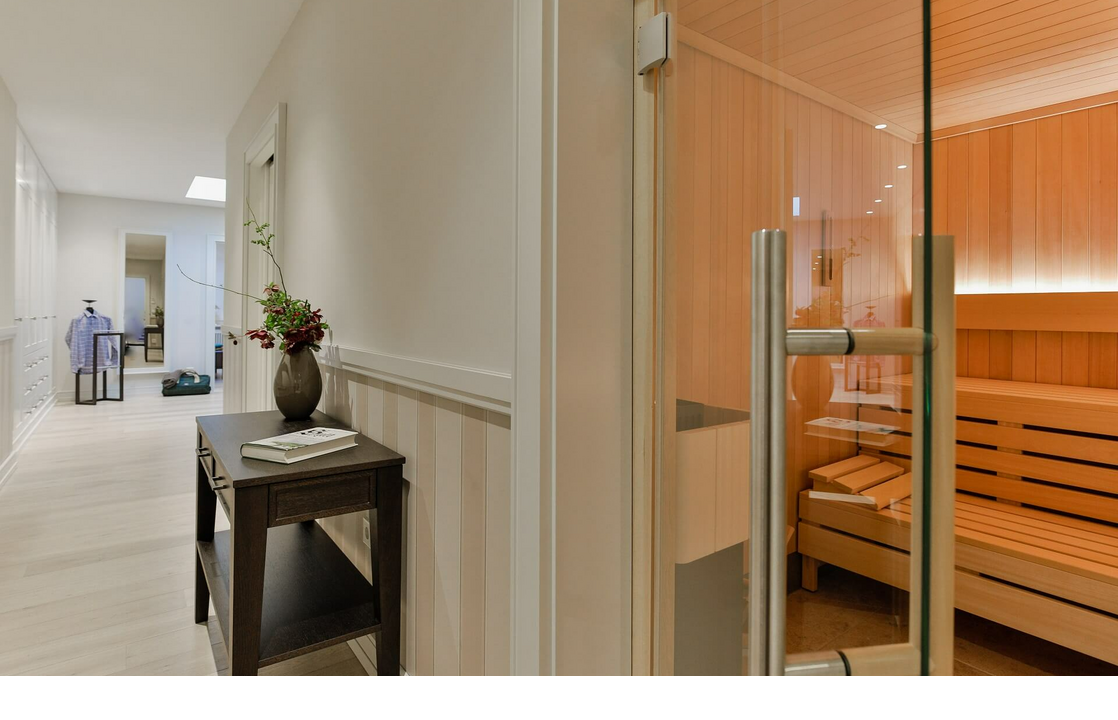 Elegant hallway with wooden table and flowers, next to a modern sauna with glass front at Severin*s Resort & Spa on Sylt.