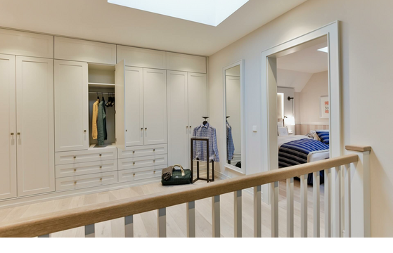 Bright dressing room at Severin*s Resort with open wardrobes and a view into the cozy bedroom.