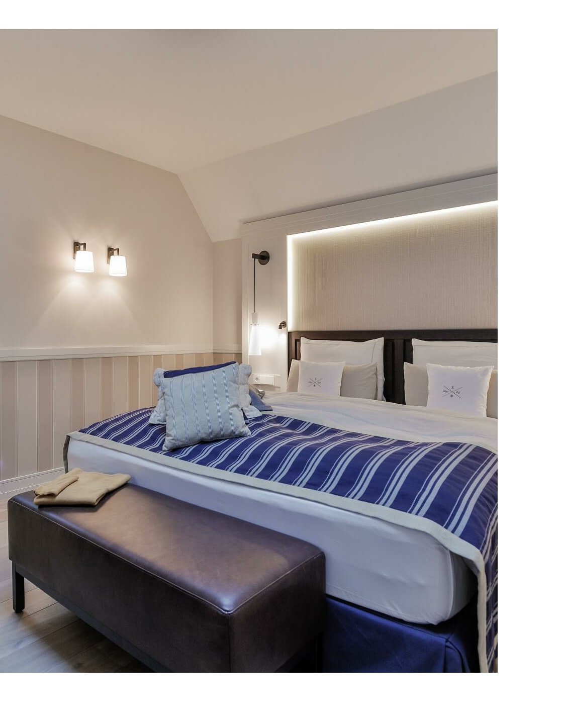 Elegantes Hotelzimmer mit Kingsize-Bett, blauer Decke und stilvoller Beleuchtung im Severin*s Resort & Spa auf Sylt.