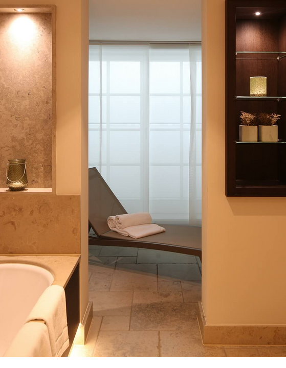 Elegantes Badezimmer mit freistehender Badewanne, Liegestuhl und dekorativen Regalen im Severin*s Resort & Spa.