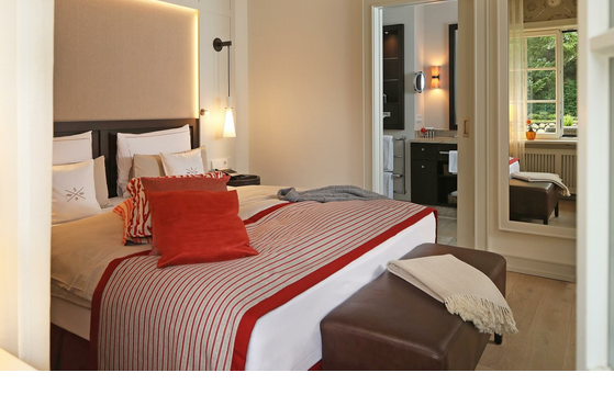 Luxuriöses Hotelzimmer mit gemütlichem Bett, eleganten Kissen, modernem Bad und Blick ins Grüne im Severin*s Resort.