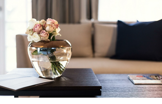 Vase with roses on an elegant wooden table in front of a beige couch at Severin*s Resort & Spa on Sylt.