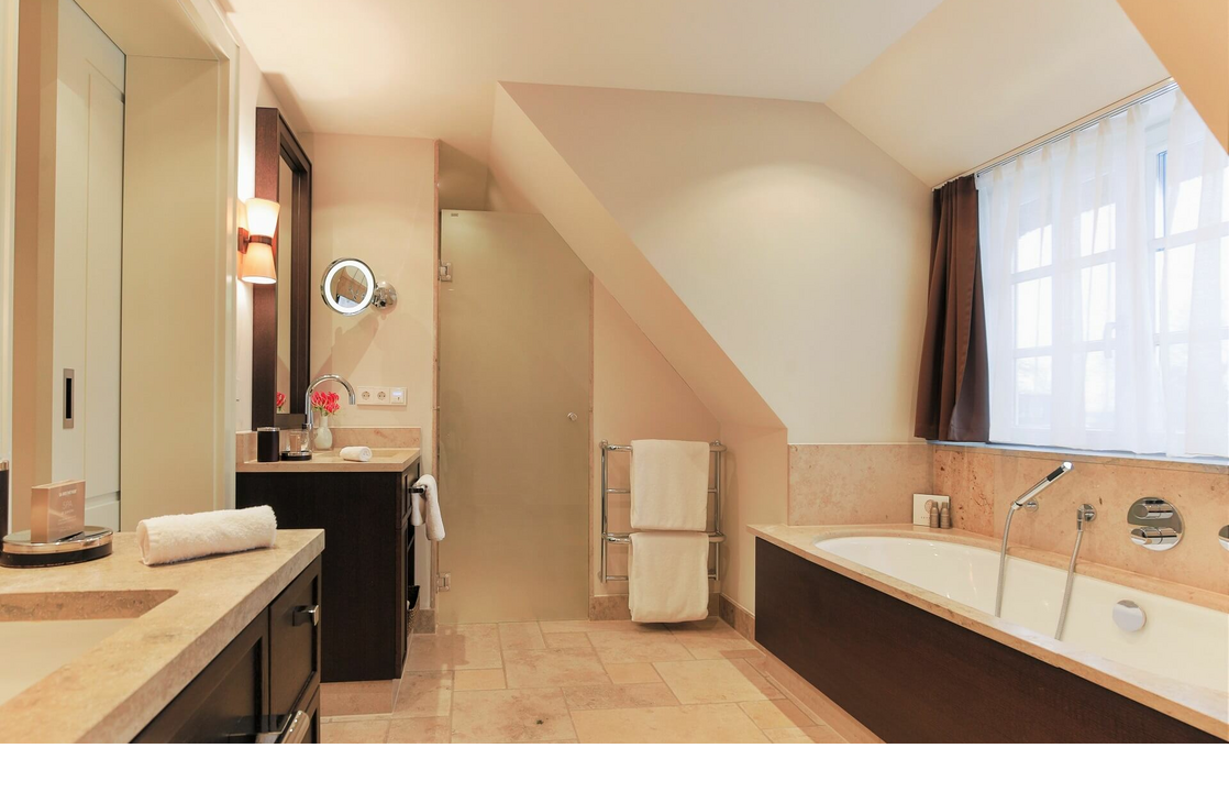 Luxurious bathroom at Severin*s Resort & Spa with bathtub, washbasin and window, elegant and modern design.