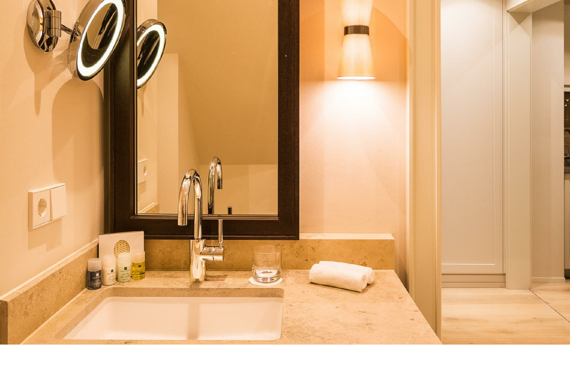 Luxuriöses Badezimmer mit beleuchtetem Spiegel, Waschbecken, Handtuch und Pflegeprodukten im Severin*s Resort & Spa.