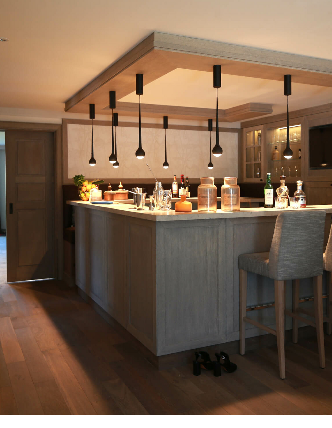 Elegant hotel bar with wooden counter, bar stools and stylish lighting at Severin*s Resort & Spa on Sylt.