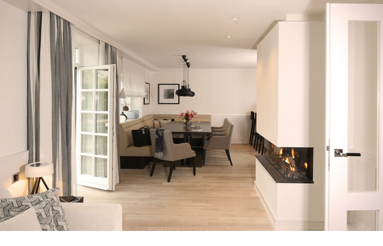 Elegantes Wohnzimmer im Severin*s Resort, Sylt: Helle Einrichtung, Kamin, Esstisch, bequeme Sitzgelegenheiten.