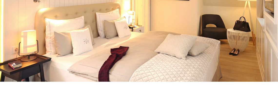 Elegantes Hotelzimmer mit großem Bett, stilvoller Beleuchtung und gemütlicher Sitzecke im Severin*s Resort & Spa, Sylt.