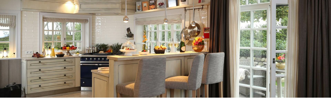 Elegante Hotelküche mit Barhockern, gedeckter Theke und Blick auf Terrasse durch große Fenster.