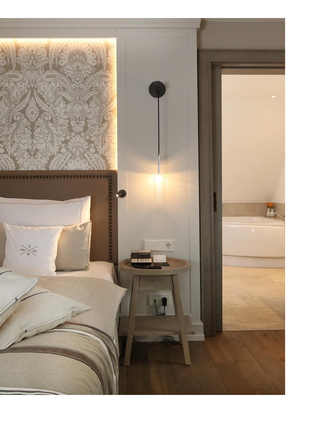 Luxuriöses Hotelzimmer mit elegantem Doppelbett, stilvoller Beleuchtung und Zugang zu einem modernen Badezimmer.