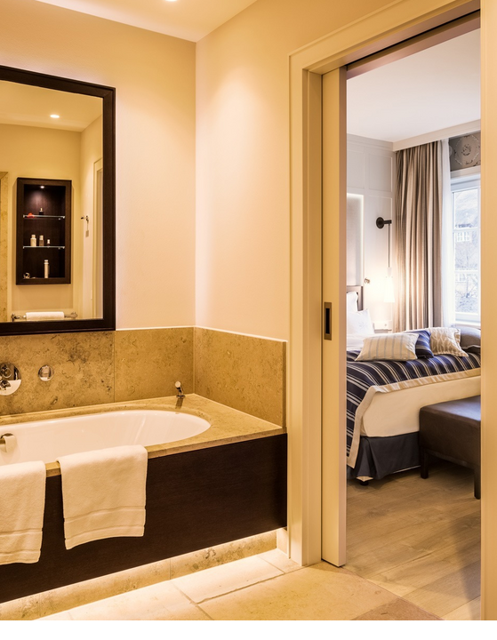 Luxuriöses Badezimmer mit Badewanne, Blick ins elegante Schlafzimmer im Severin*s Resort & Spa auf Sylt.