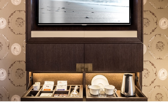 Luxuriöse Hotelzimmerausstattung mit eingebautem TV, Minibar und stilvollen Tee- und Kaffeebereitern.