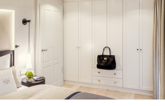 Bright hotel room with elegant bed, white wardrobes and modern lighting at Severin*s Resort & Spa on Sylt.