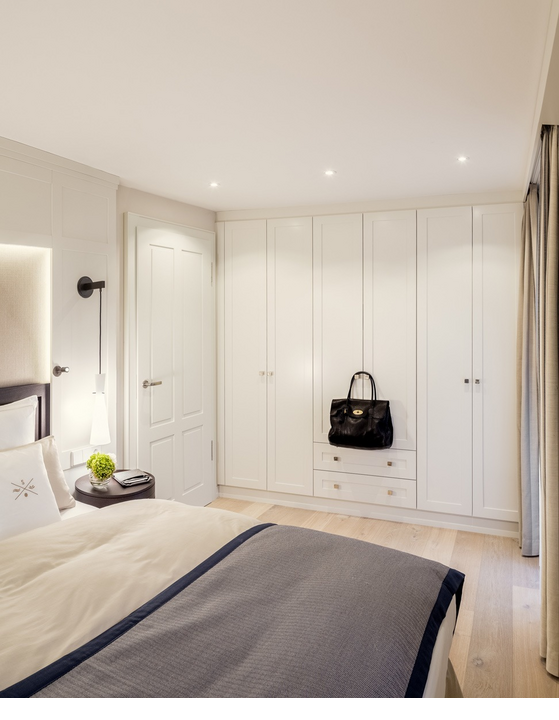 Helles Hotelzimmer mit elegantem Bett, weißen Schränken und moderner Beleuchtung im Severin*s Resort & Spa auf Sylt.