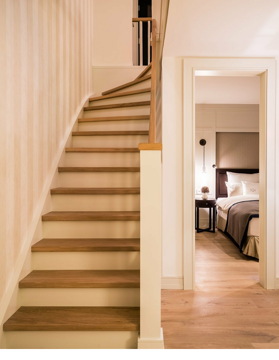 Holztreppe und elegantes Schlafzimmer im Severin*s Resort & Spa auf Sylt, mit stilvoller Beleuchtung und hochwertiger Ausstattung.
