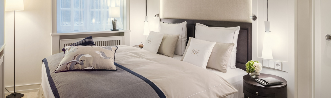 Elegantes Hotelzimmer mit Doppelbett, stilvoller Beleuchtung und modernen Möbeln im Severin*s Resort & Spa auf Sylt.