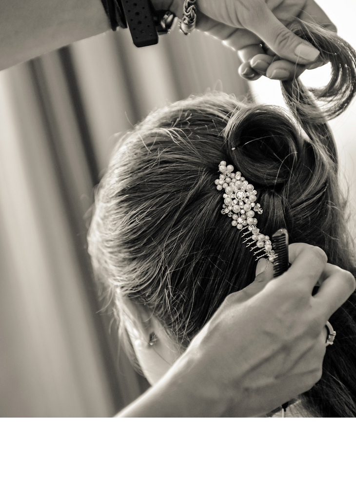 Person is styled, with hair ornaments made of pearls and flowers in the hair, in an elegant ambience.