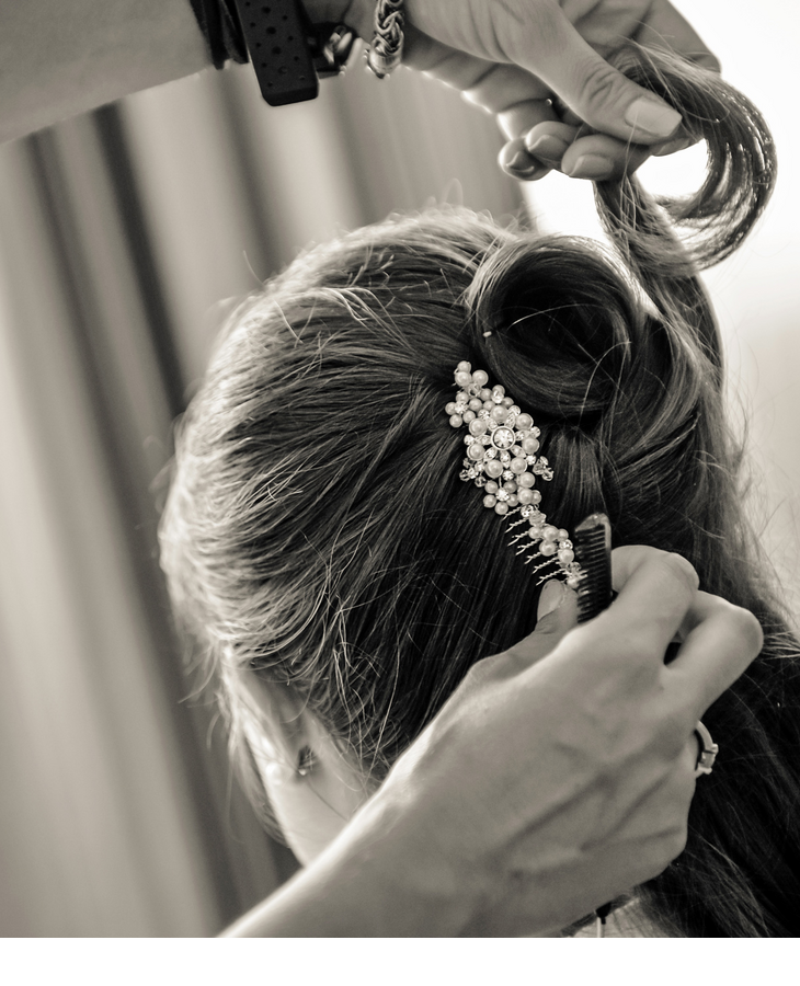 Person is styled, with hair ornaments made of pearls and flowers in the hair, in an elegant ambience.