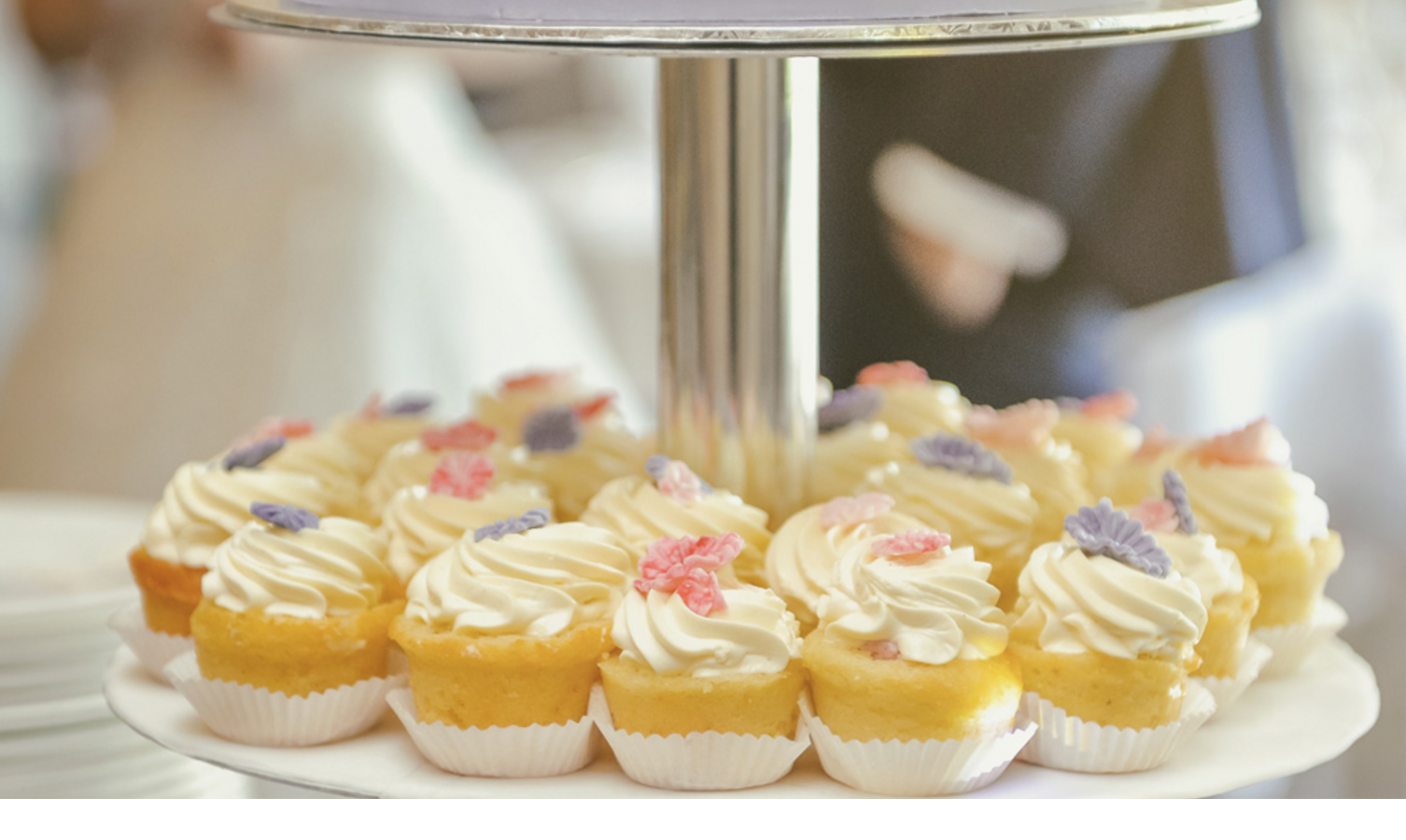 Etagere with wedding cake and cupcakes, decorated with colorful flowers, at Severin*s Resort & Spa on Sylt.