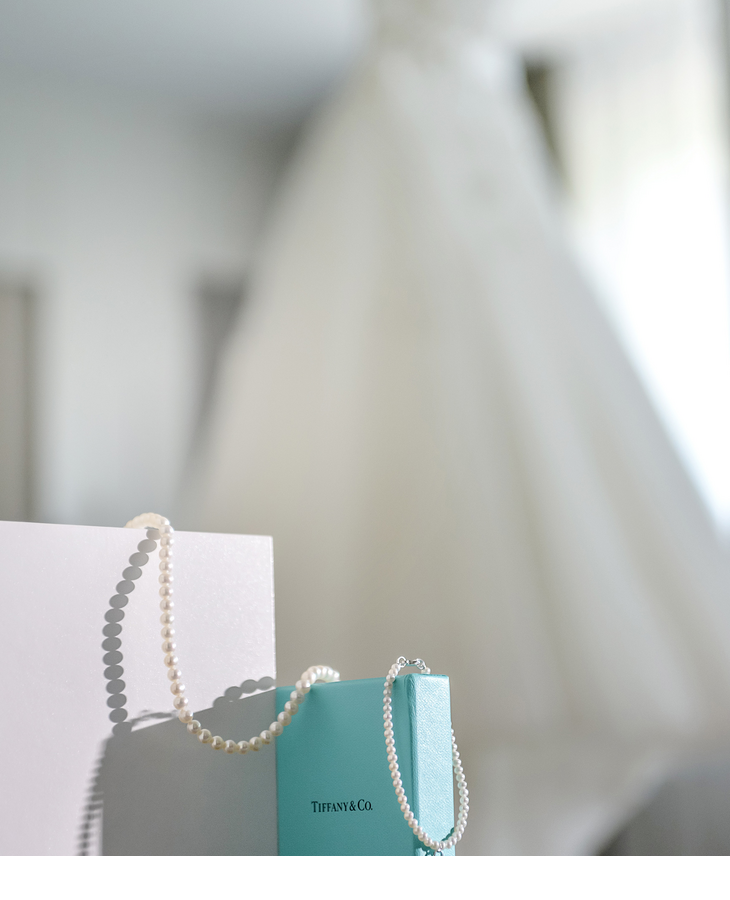 Pearl necklace on a Tiffany box, blurred wedding dress in the background, elegant atmosphere at Severin*s Resort & Spa.