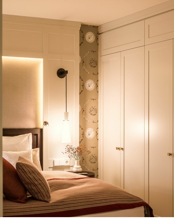 Elegant hotel room with cozy bed, stylish lighting and modern wallpaper at Severin*s Resort & Spa on Sylt.