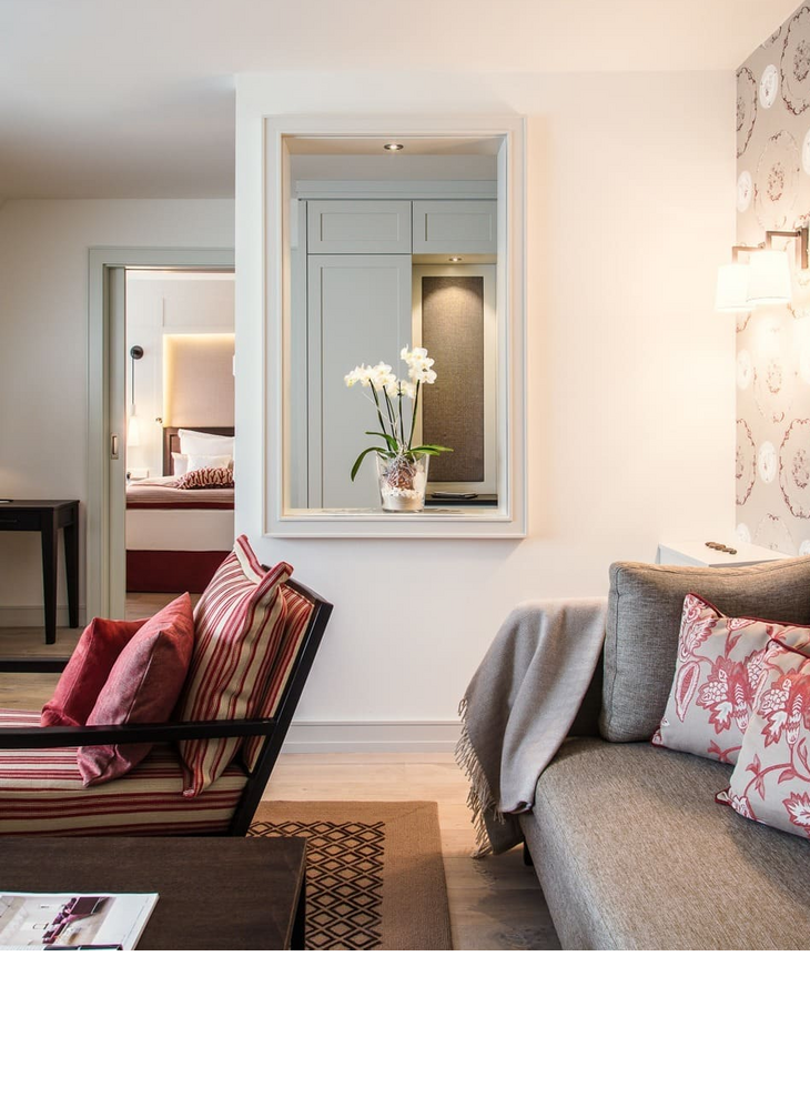 Living area with sofa in the junior suite at the hotel of Severin*s on Sylt Elegant living room at Severin*s Resort & Spa with stylish furniture and flower arrangements.