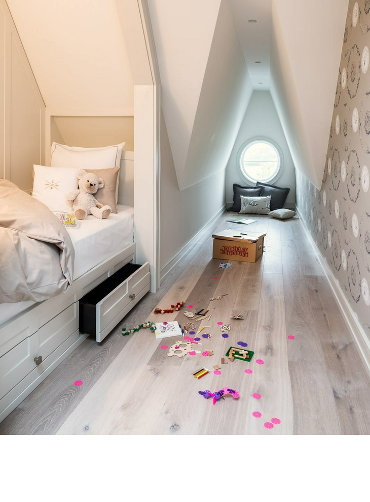 Innenansicht mit Kinderbett der Maisonette Junior Family Suite im Hotel Severin*s Resort und Spa auf Sylt Helles Kinderzimmer mit Einzelbett, Kuscheltier, Spielzeug auf dem Boden und rundem Fenster im Severin*s Resort & Spa.