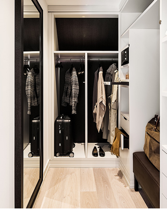 Modern walk-in closet at Severin*s Resort & Spa with mirror, clothes and luggage.