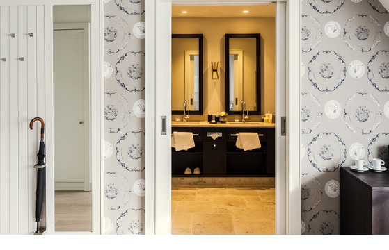 Elegantes Hotelzimmer mit stilvoller Tapete, Spiegel, Schiebetür zum Badezimmer und moderner Einrichtung.