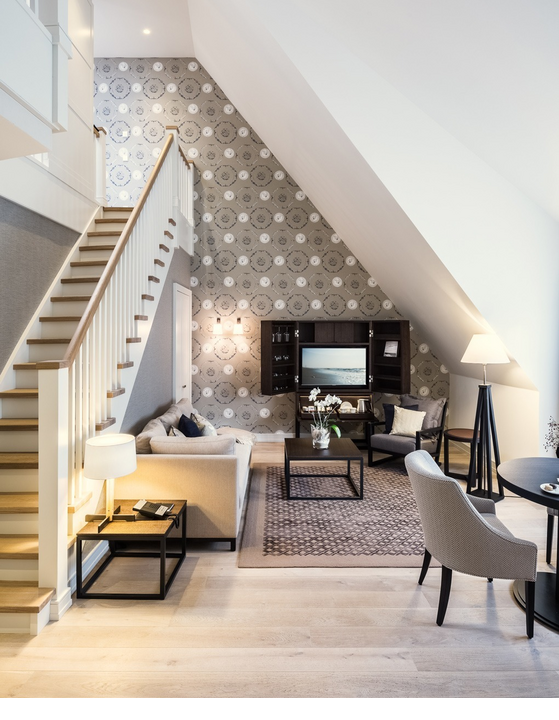 Elegantes Wohnzimmer mit Treppe, Sofa, TV, Teppich und stilvollen Möbeln im Severin*s Resort & Spa auf Sylt.