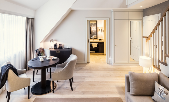 Elegantes Hotelzimmer mit gemütlicher Sitzecke, Esstisch, Sofa und Blick ins stilvolle Badezimmer im Severin*s Resort & Spa.