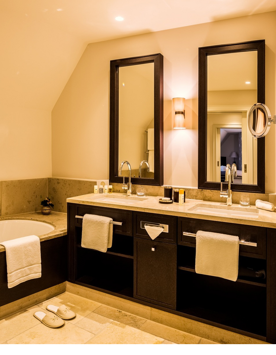 Luxurious bathroom at Severin*s Resort & Spa with double washbasin, bathtub and elegant lighting.