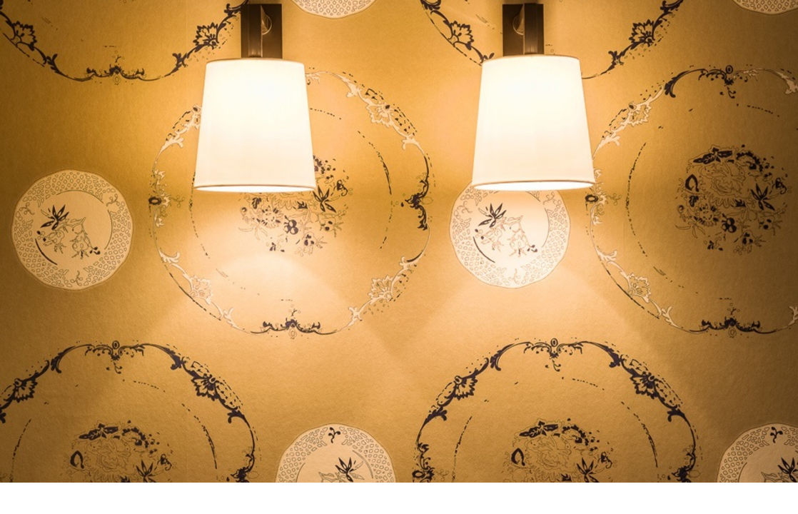 Two elegant wall lamps on patterned wallpaper at Severin*s Resort & Spa on Sylt.