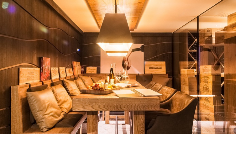 Gemütliche Weinlounge mit Holztisch, Ledersitzen, sanfter Beleuchtung und Weinflaschen im Severin*s Resort & Spa.