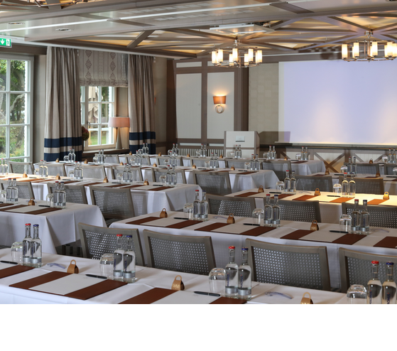 Eleganter Konferenzraum mit gedeckten Tischen, Schreibmaterialien und Wasserflaschen im Severin*s Resort & Spa auf Sylt.